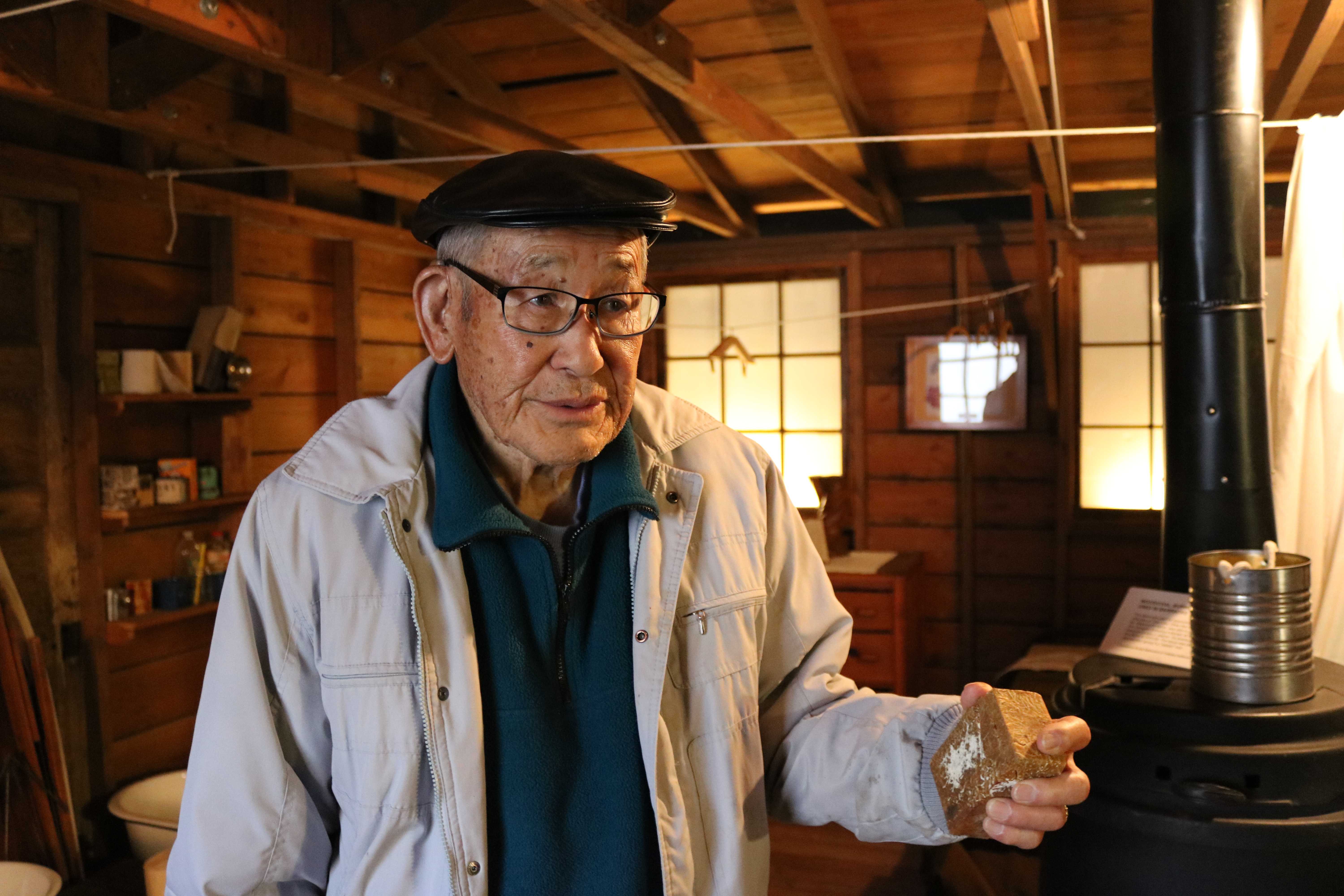 Jimi Yamaichi holds a brick that he brought back from Tule Lake inside a recreation of the barracks at the Japanese-American Museum of San Jose. Click to read his story. Photo by Gabriela Rossner.