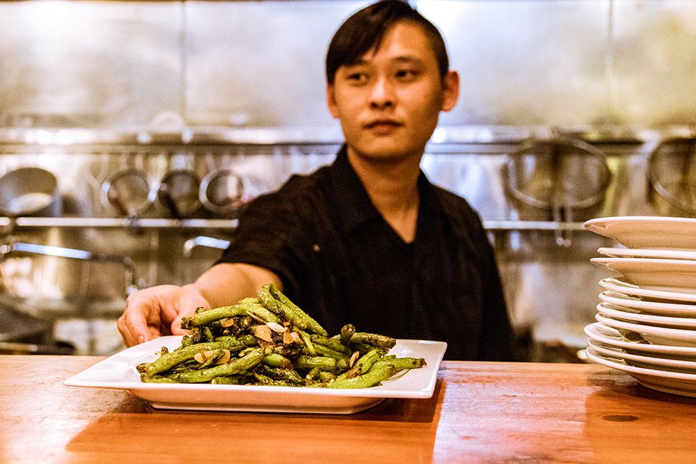 Chef Xiao Li, 35, places his steaming, sauteed greenbean masterpiece, the Dry Fried Green Bean dish, on the counter for the servers to deliver to the customers. 