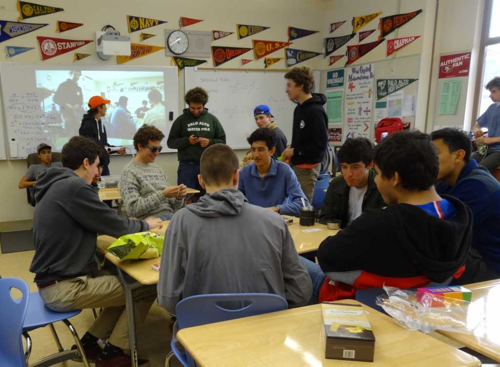 Board game members play a card game and enjoy snacks in room 860.