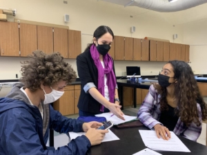 SUBSTITUTE SUPPORT — Substitute teacher Mary Haddad guides juniors Maya Mukherjee and Felix Blanch through a physics assignment. “Substitute teachers do really hard and underappreciated work.” Mukherjee said. Photo: Annum Hashmi
