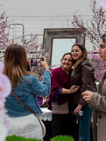 CAPTURING CELEBRATION — Two friends pose for a picture in front of the haft-sin at the festival. The festival draws in hundreds of people every year. “This event [Nowruz festival and bazaar] happens every year,” event coordinator Gita Meshkat said. “This is like our Christmas.”