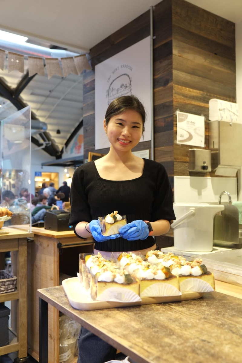 STOCKING UP THE SWEETS — Ikuka owner Miyuka Ozawa neatly arranges a tray of her shop’s signature Kabocha Burnt Basque Cheesecakes to display at Ikuka’s Los Altos State Street Market stall. “Our pastries are made in a separate kitchen.” Ozawa said. “I deliver the cakes here every morning.” 
