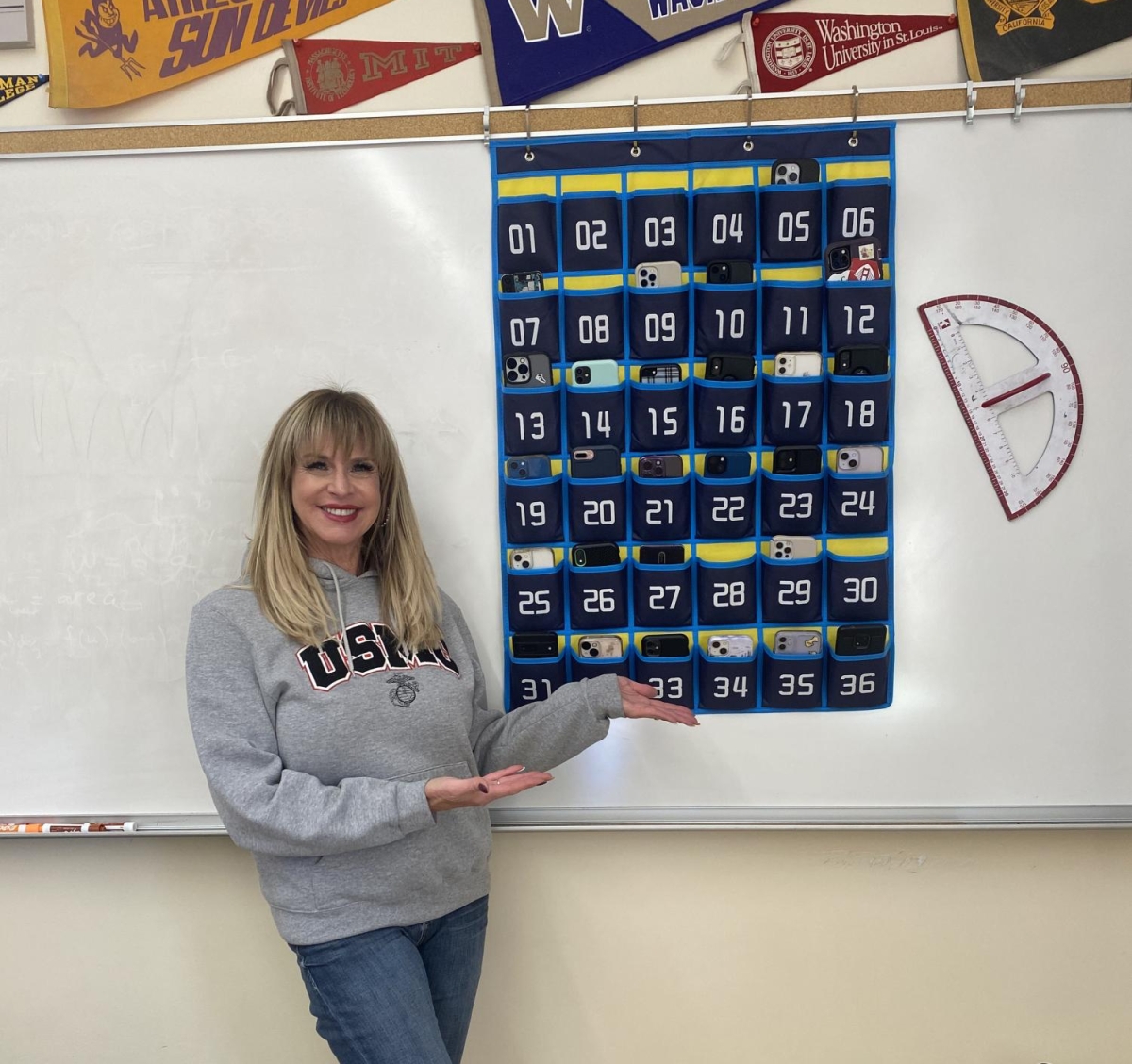 PHONES AWAY — Paly math teacher Misha Stempel poses in front of her classroom’s phone holder. “Having phones on person is very distracting for a lot of students,” Paly science teacher Nicole Loomis said. 