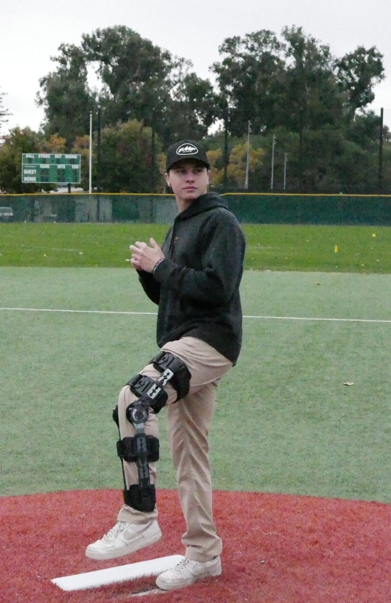 RECIPE FOR RECOVERY — Paly senior Henry Harding throws a pitch while dealing with a knee injury. “I’ve focused on just doing good in class, paying attention and getting my grades right because I have so much extra free time,” Harding said. 