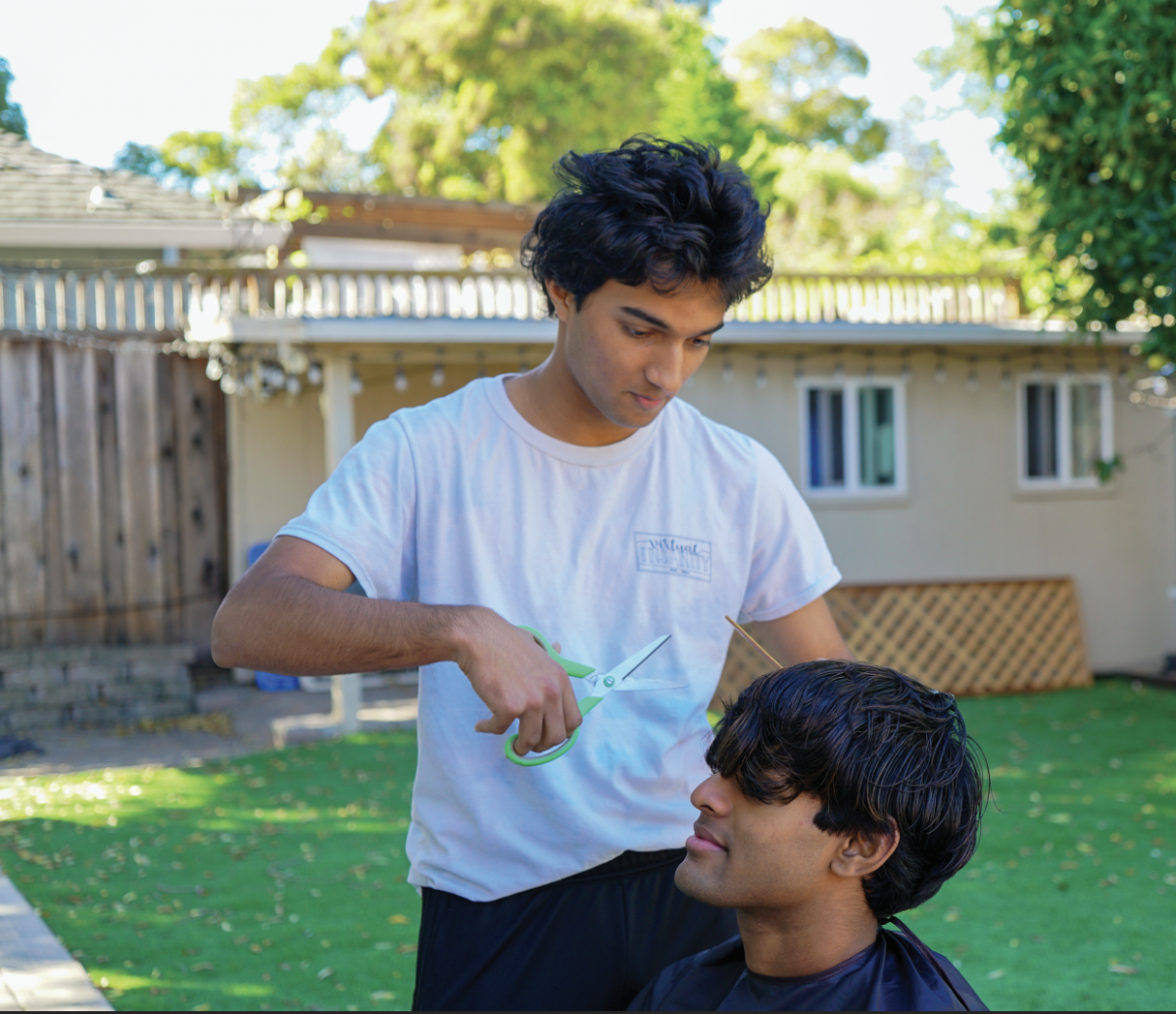 BACKYARD FADES — Hanu Thakur carefully cuts the hair of his client, Alaap Nair, a UC Berkeley student and 2024 Paly graduate. “I’m just doing it because I like to do it,” Thakur said. “I love cutting hair. ... It’s really satisfying and relaxing.” Photo: Lara Saslow