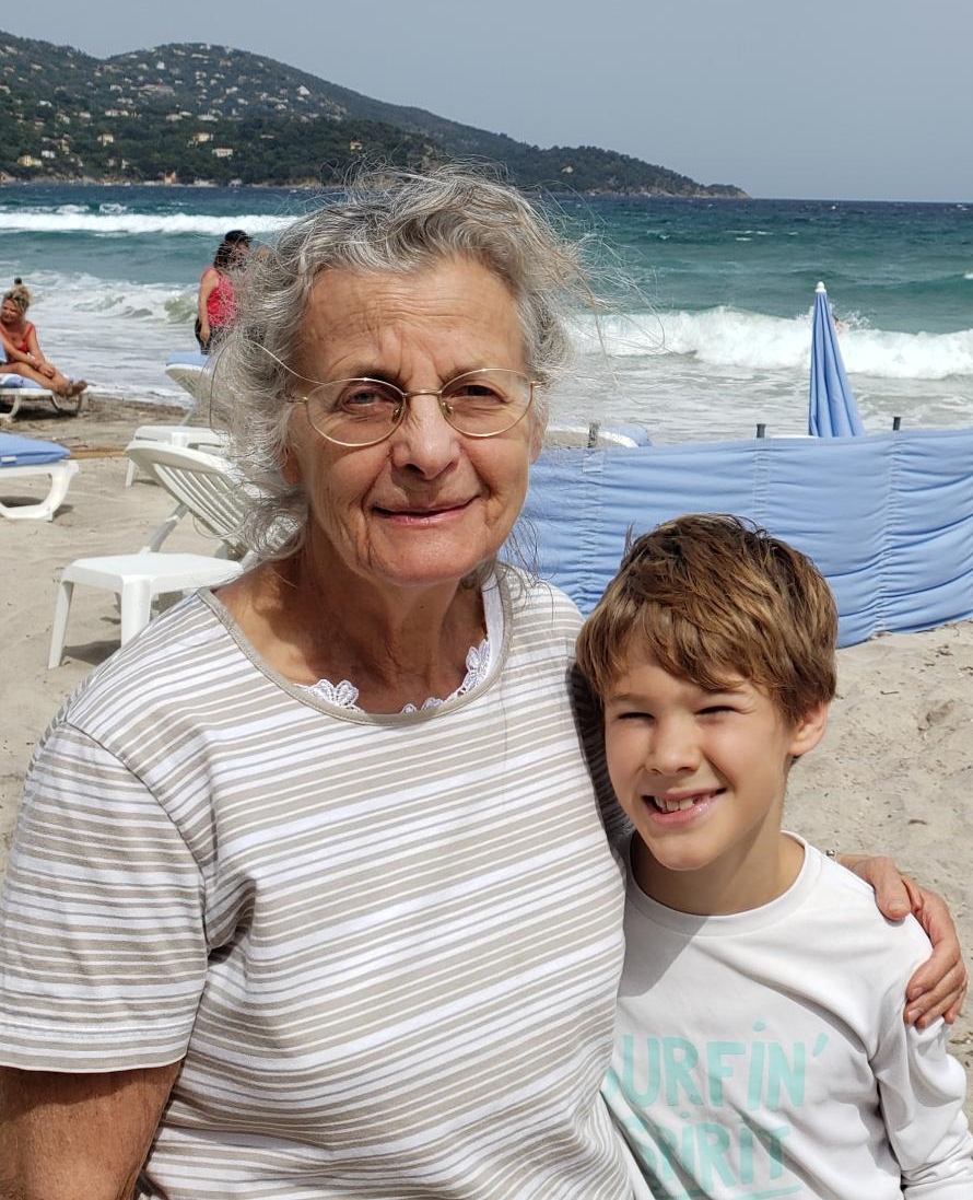 BY THE WATER — At age 10, I stand beside my grandmother on the beach in Saint-Tropez, France, her arm wrapped around me. Photo Courtesy: Michel Sayag