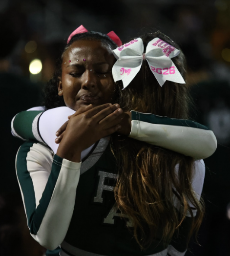 SENTIMENTAL SUCCESS — Palo Alto High School senior Ivy Hardy hugs her junior teammate, after their last performance together. On Oct. 24, Paly football, band, cheer and dance celebrated senior night.