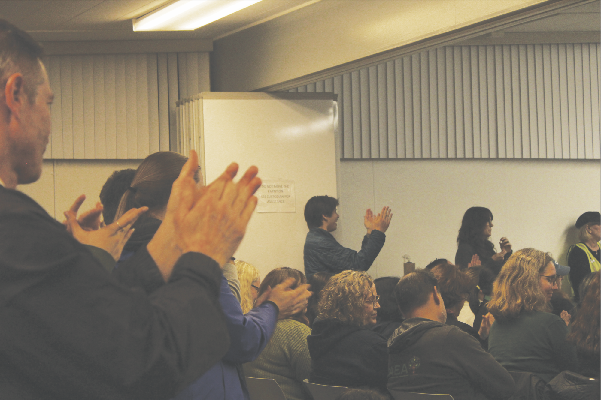 ENTHUSIASTIC APPLAUSE — The Palo Alto Unified School District community shows up to the Feb. 10 board meeting to support those who are advocating for the teacher union. Paly science teacher Samuel Howles-Banerji speaks up during the meeting. “We can't afford it, and we have to make difficult cuts,” Howles-Banerji said. “Those cuts should not come from the foundations that support students.”