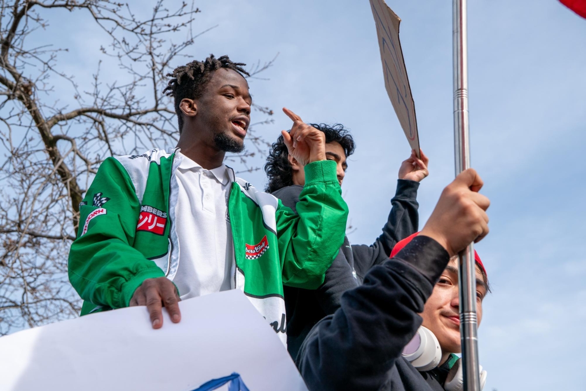 VOICING A MESSAGE — Paly junior and walkout organizer Brian talks into a microphone in front of traffic. “The youth are what start the change, and we have to be aware,” Brian said.