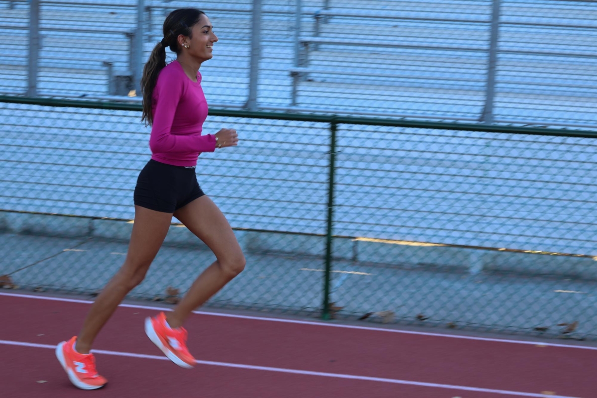 SPRINTING AHEAD — Paly senior Amaya Bharadwaj runs a warmup lap around the track during practice after school. "I'm really proud of how my running has progressed over the years," Bharadwaj said.
