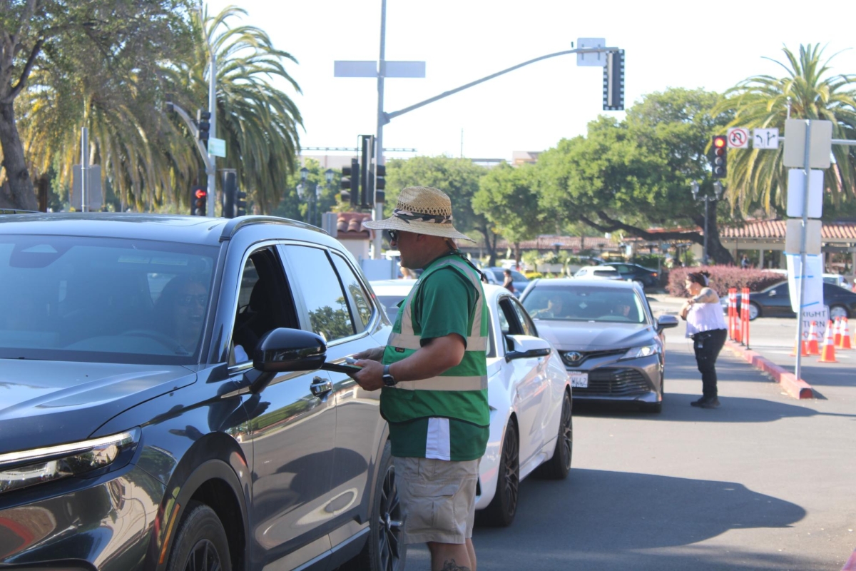 PACKED PARKING –- A volunteer speaks to a driver while negotiating a payment for a parking spot. Events at Stanford Stadium have high attendance, which in turn benefits ASB. “With the addition of Stanford now selling out concerts and doing more events in their stadium, I think it's good that we have a backup plan and a new source of revenue,” Singhal said.